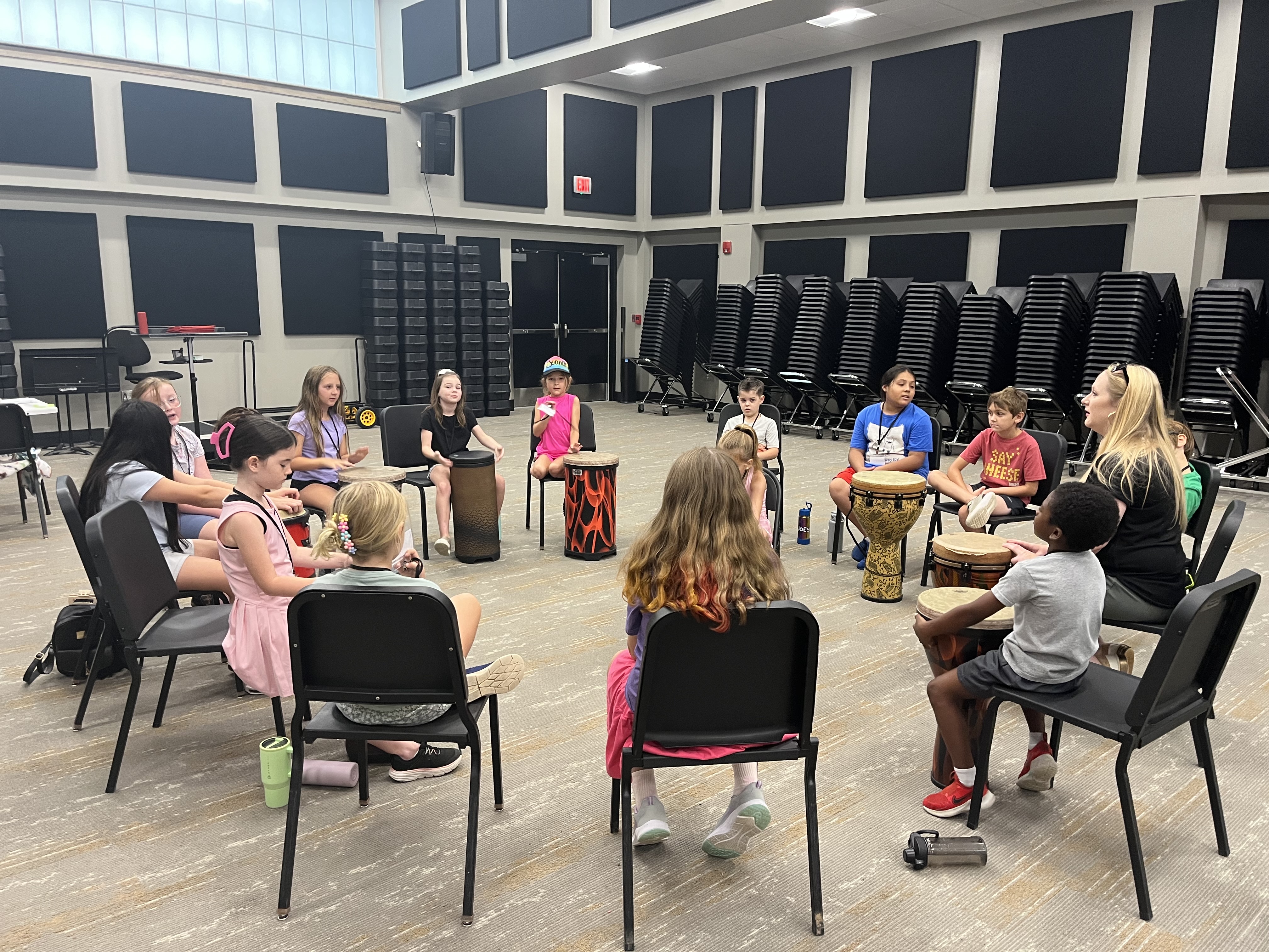 Mandy Quinn leading a percussion circle with elementary students on djembe drums